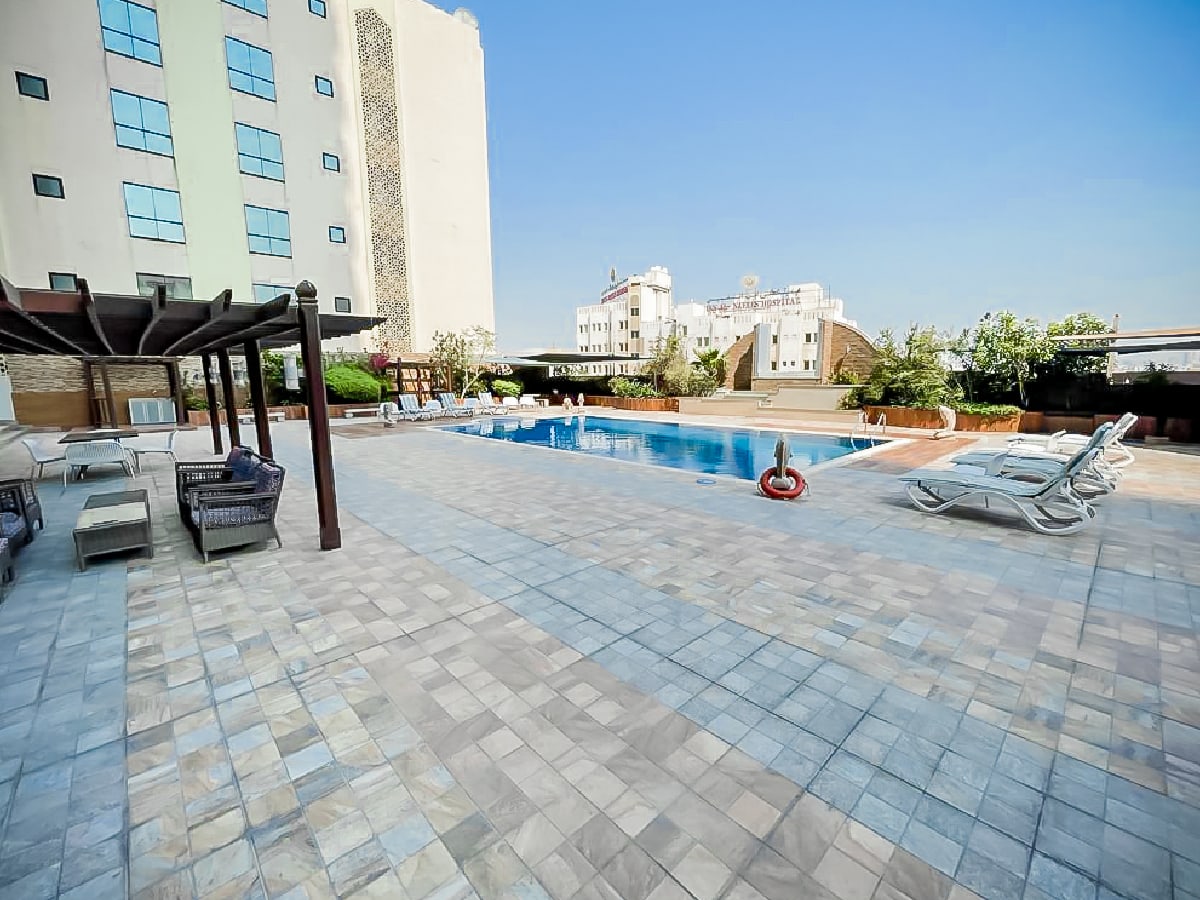 Luxury apartment featuring a swimming pool and lounge chairs in Al Mahooz area.