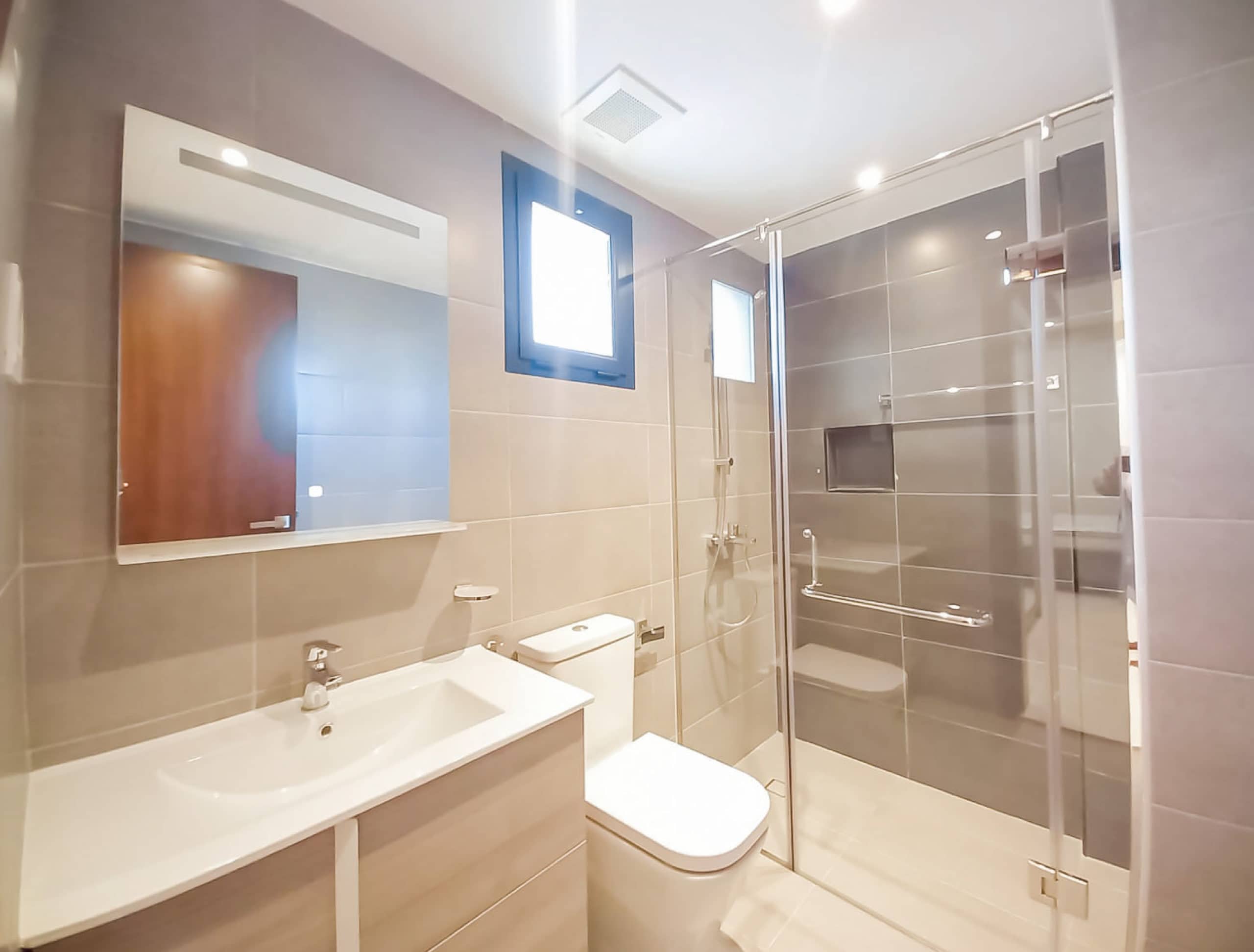 Spacious bathroom with a glass shower stall and toilet.