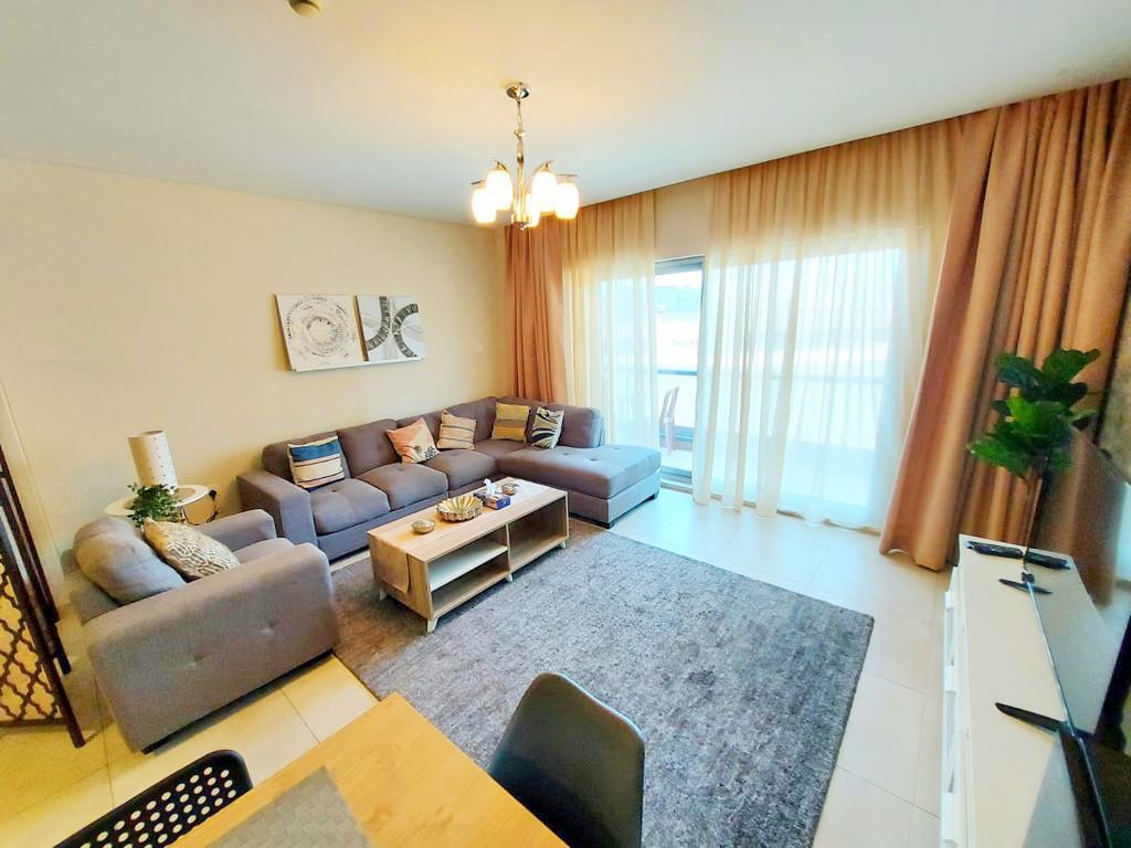 A modern living room with a couch and dining table, featuring a balcony.