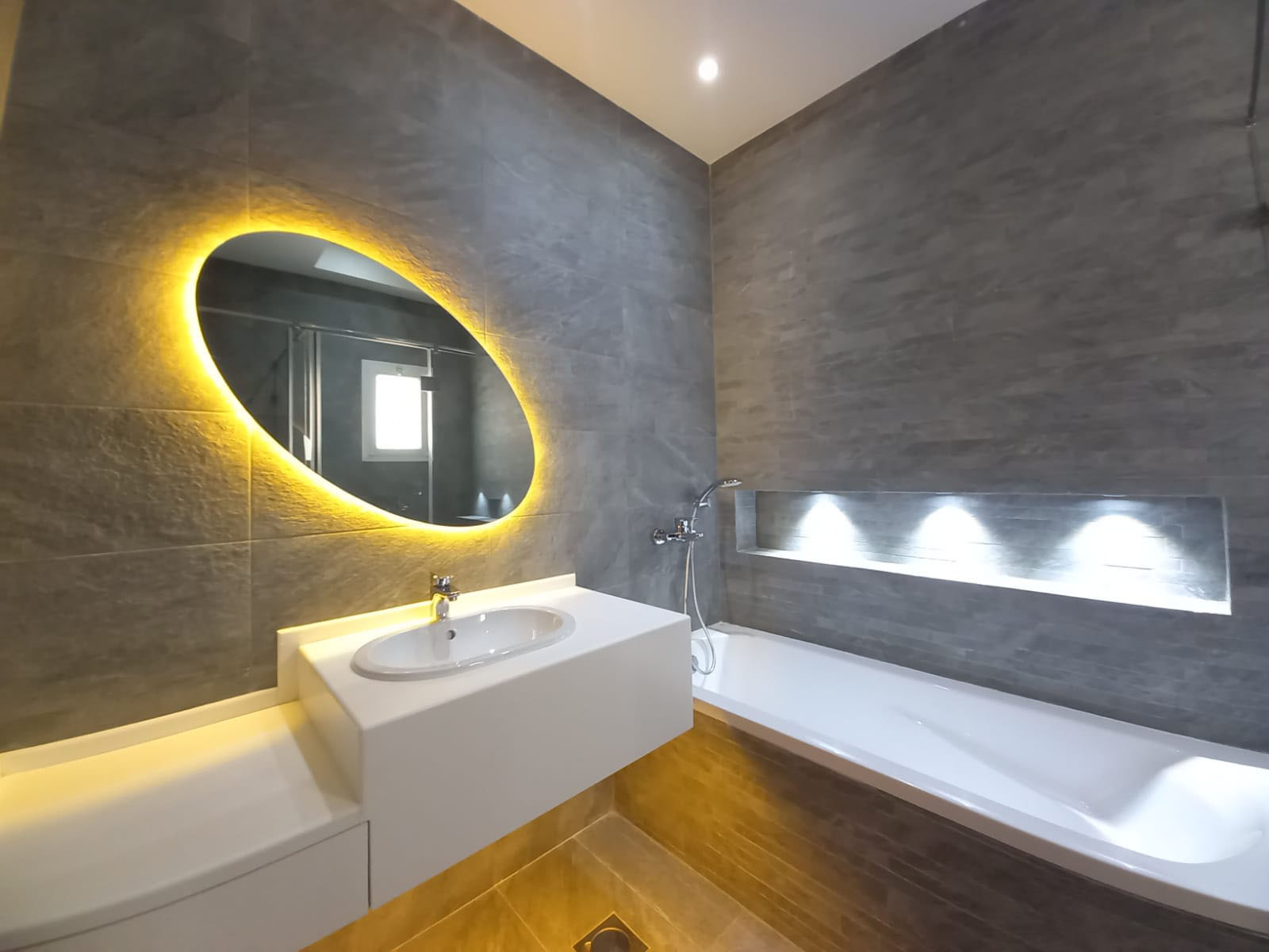 A modern 3BR villa for rent in Janabiyah with a round mirror and yellow lighting.