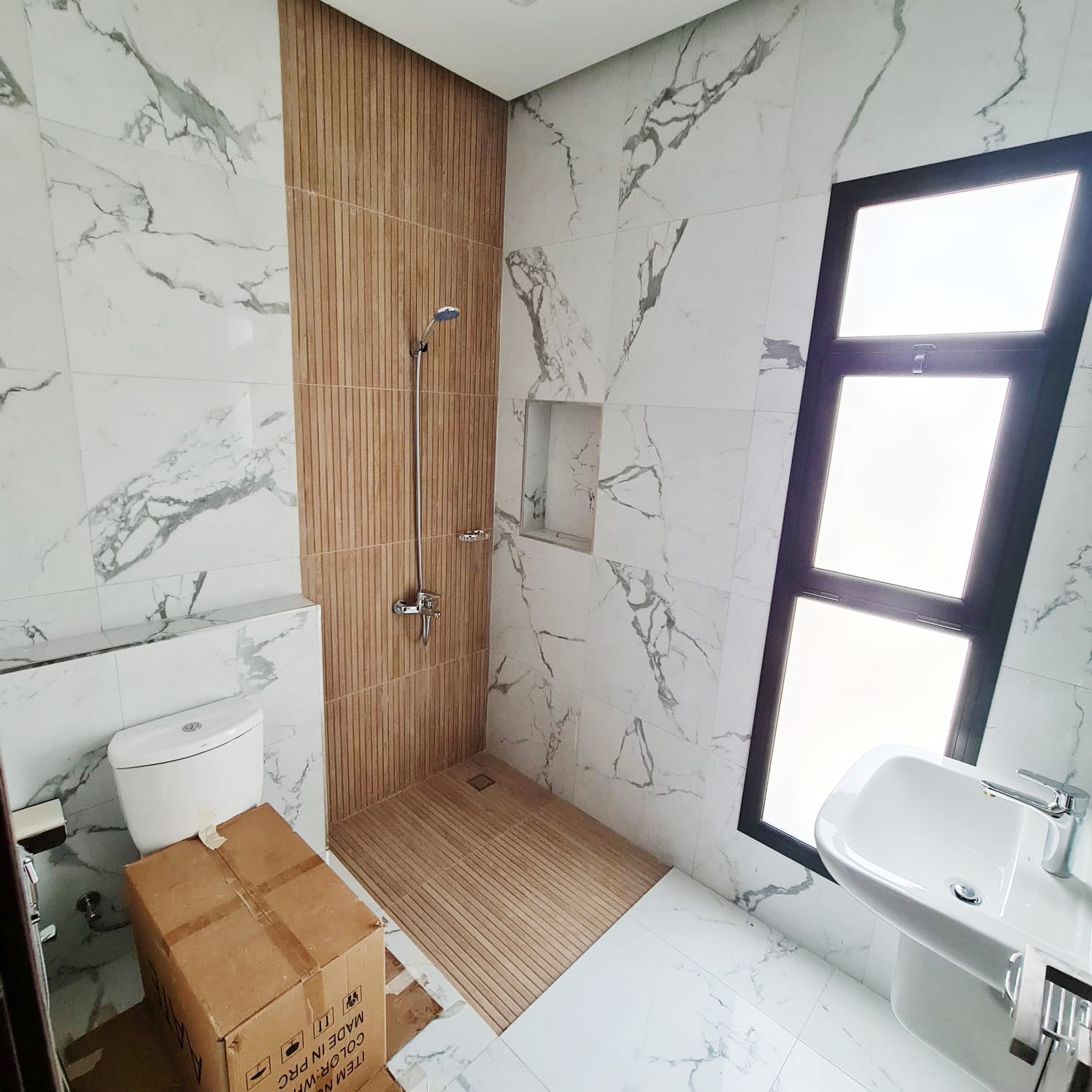 A brand new bathroom with marble walls and a toilet.