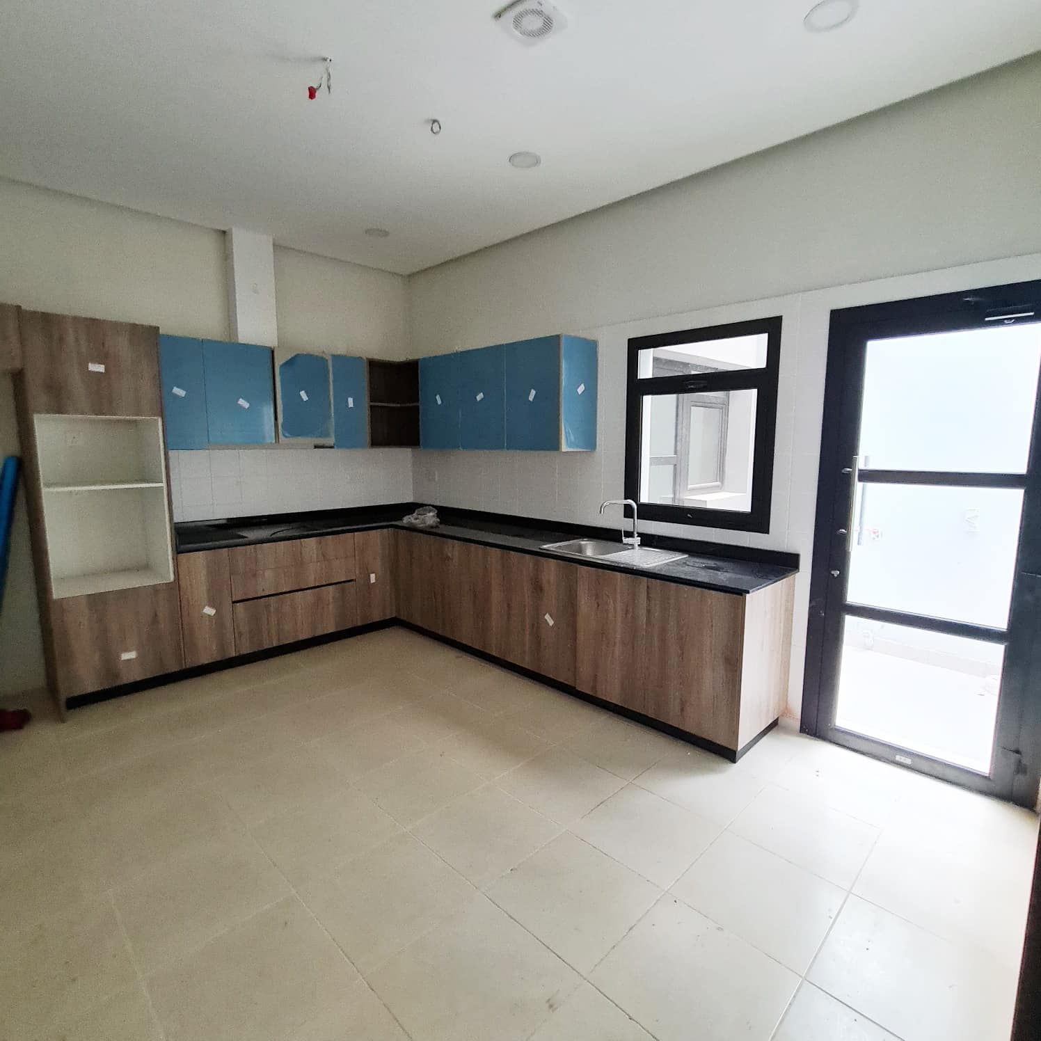 A brand new kitchen with blue cabinets and a door in a villa for sale in Barbar.