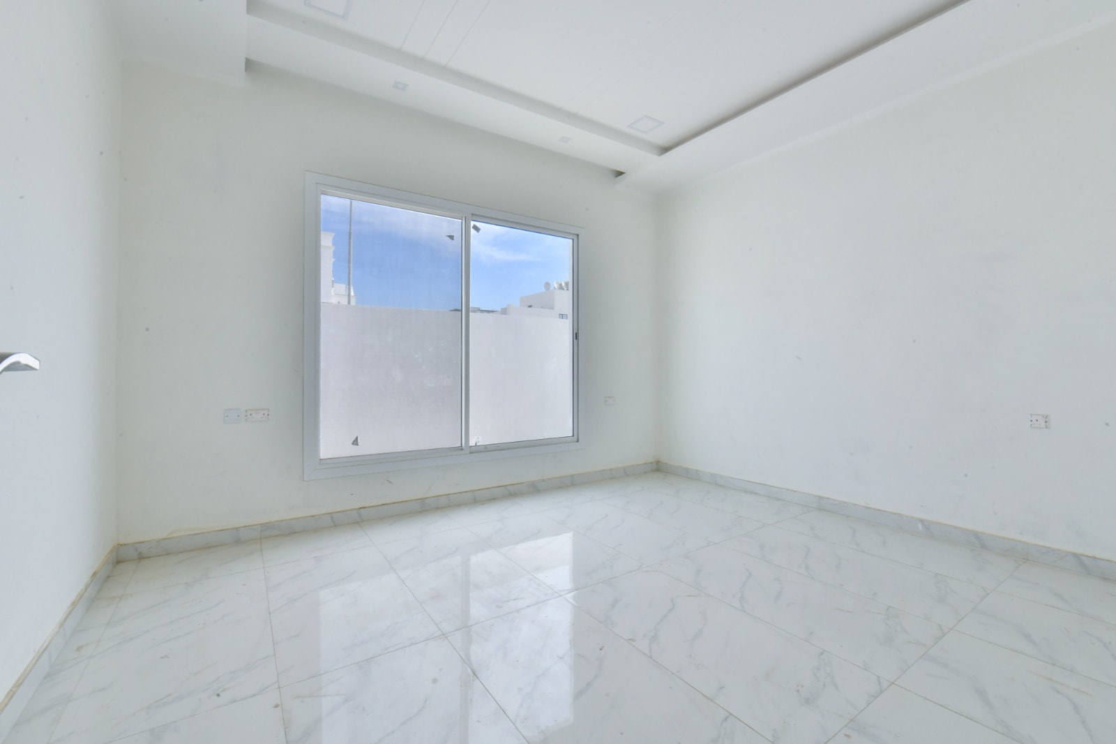 A white tiled room with a window and a door in an amazing villa.