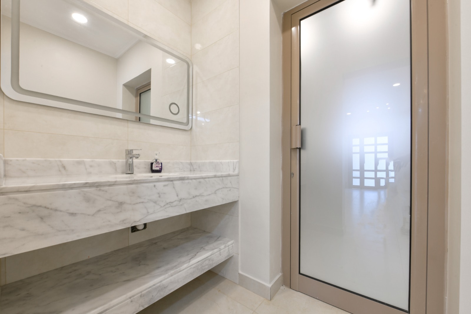 A stunning bathroom with a glass door and marble counter top.