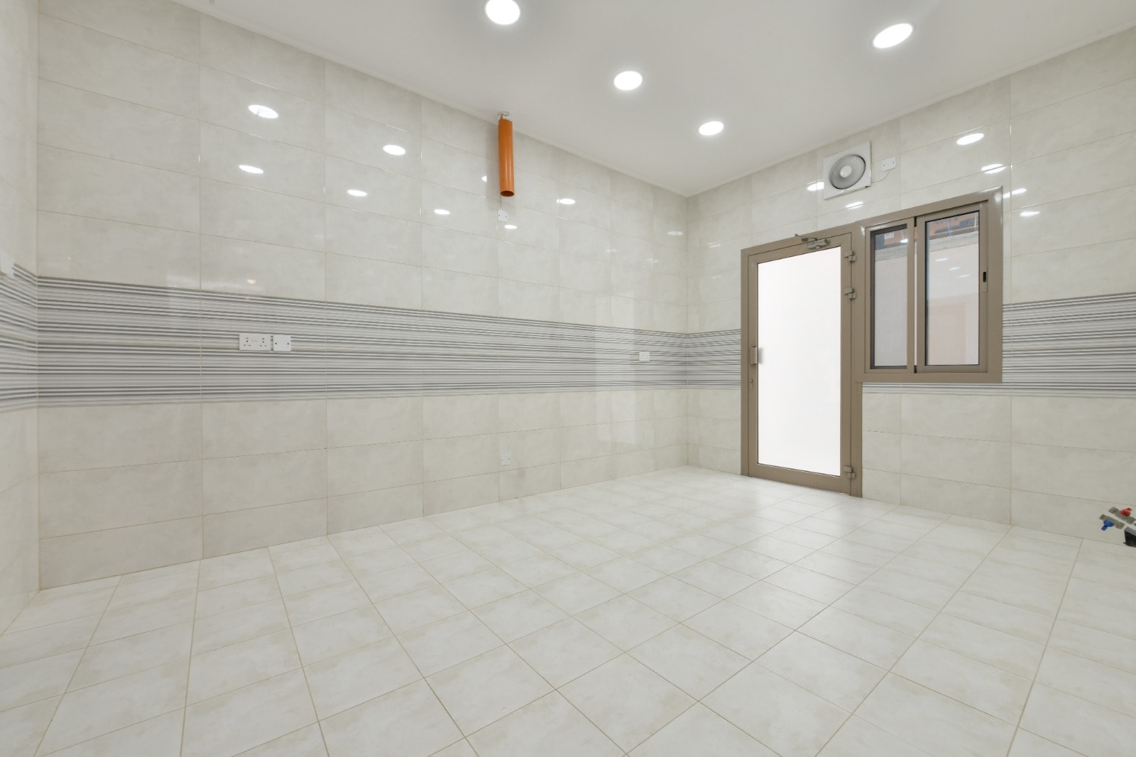 A white-tiled bathroom with a door.