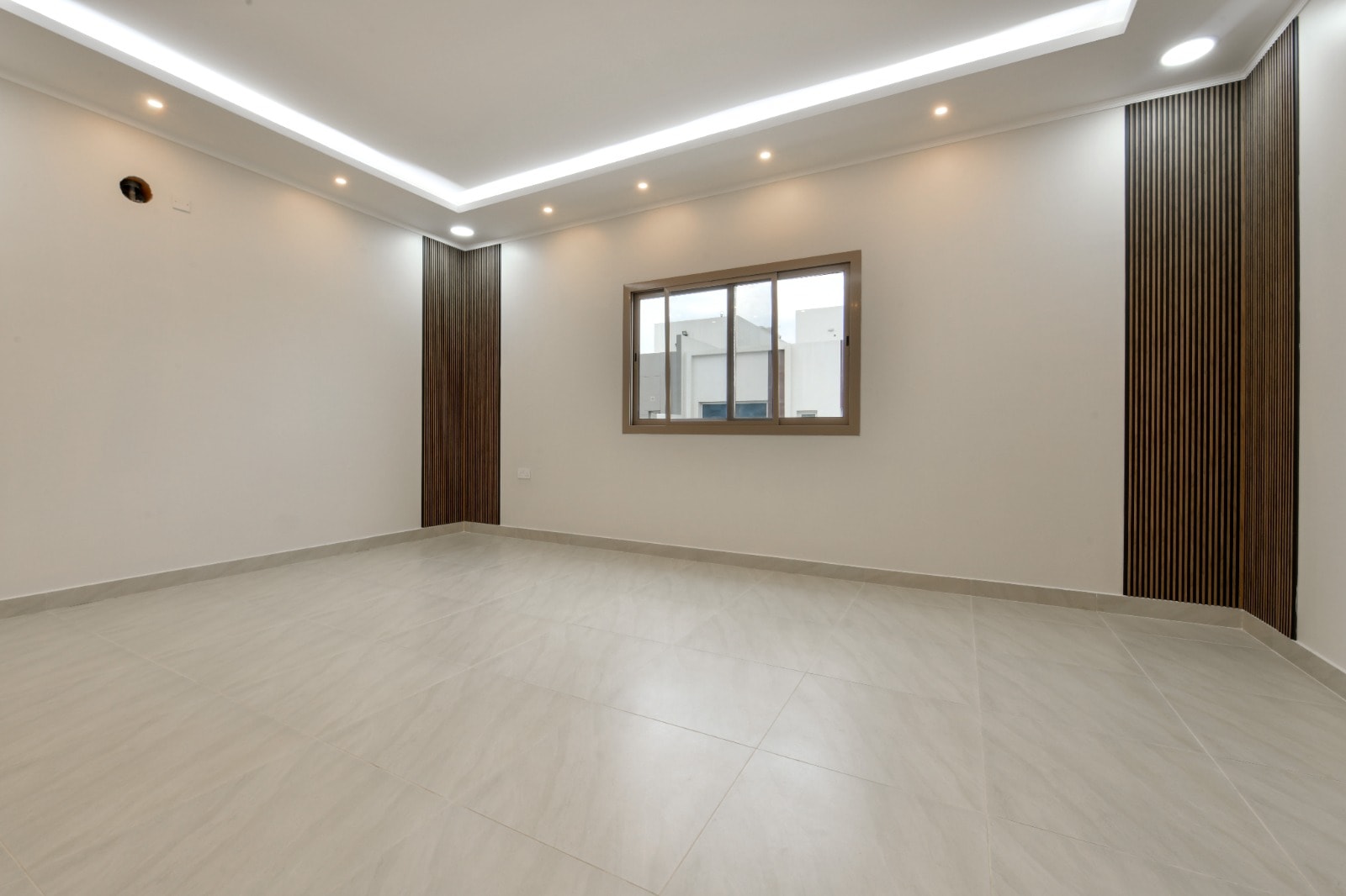 An empty room with white walls and a window in an amazing villa for sale.