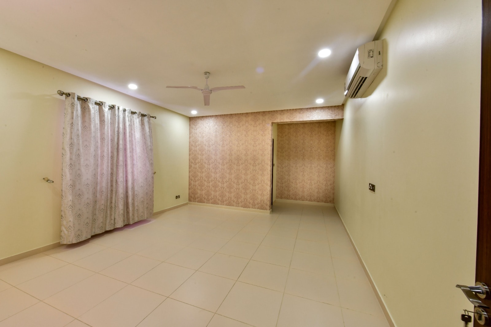 An empty room with tiled walls and a ceiling fan available in a luxury 4BR Villa for Rent in Janabiyah.