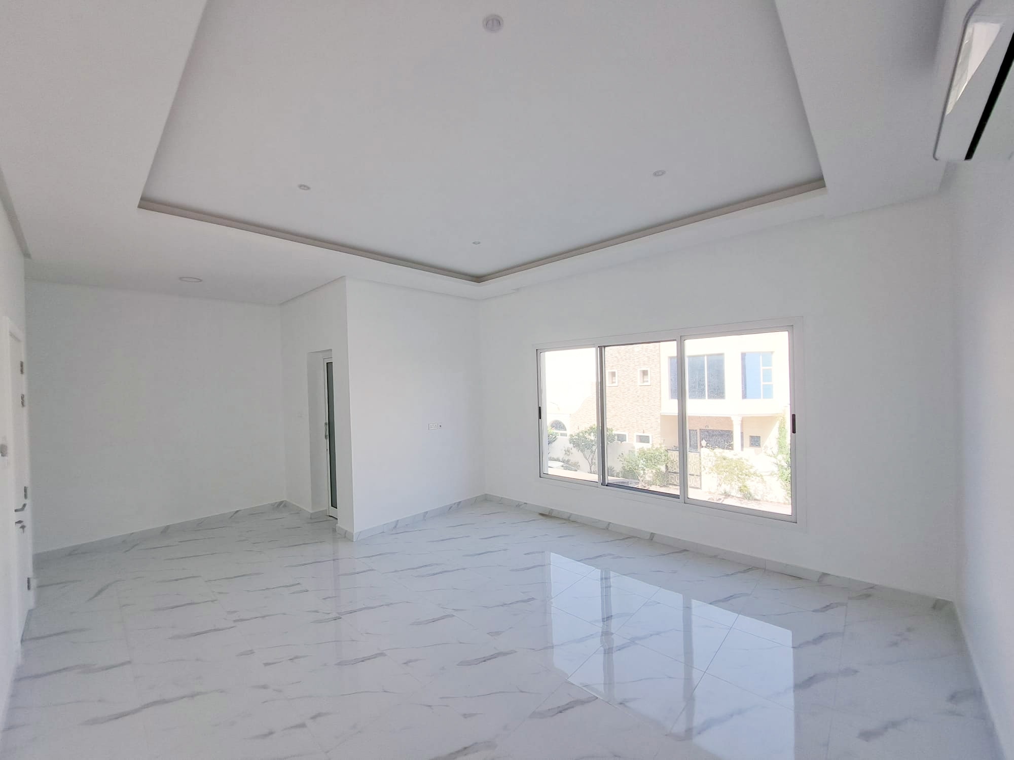 A luxurious 4BR Villa in Al Shakhura with an empty room featuring white walls and tile floors.