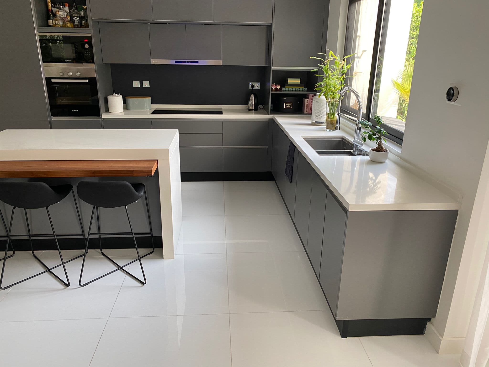 A modern kitchen with fully furnished white cabinets and sleek black counter tops available for rent.