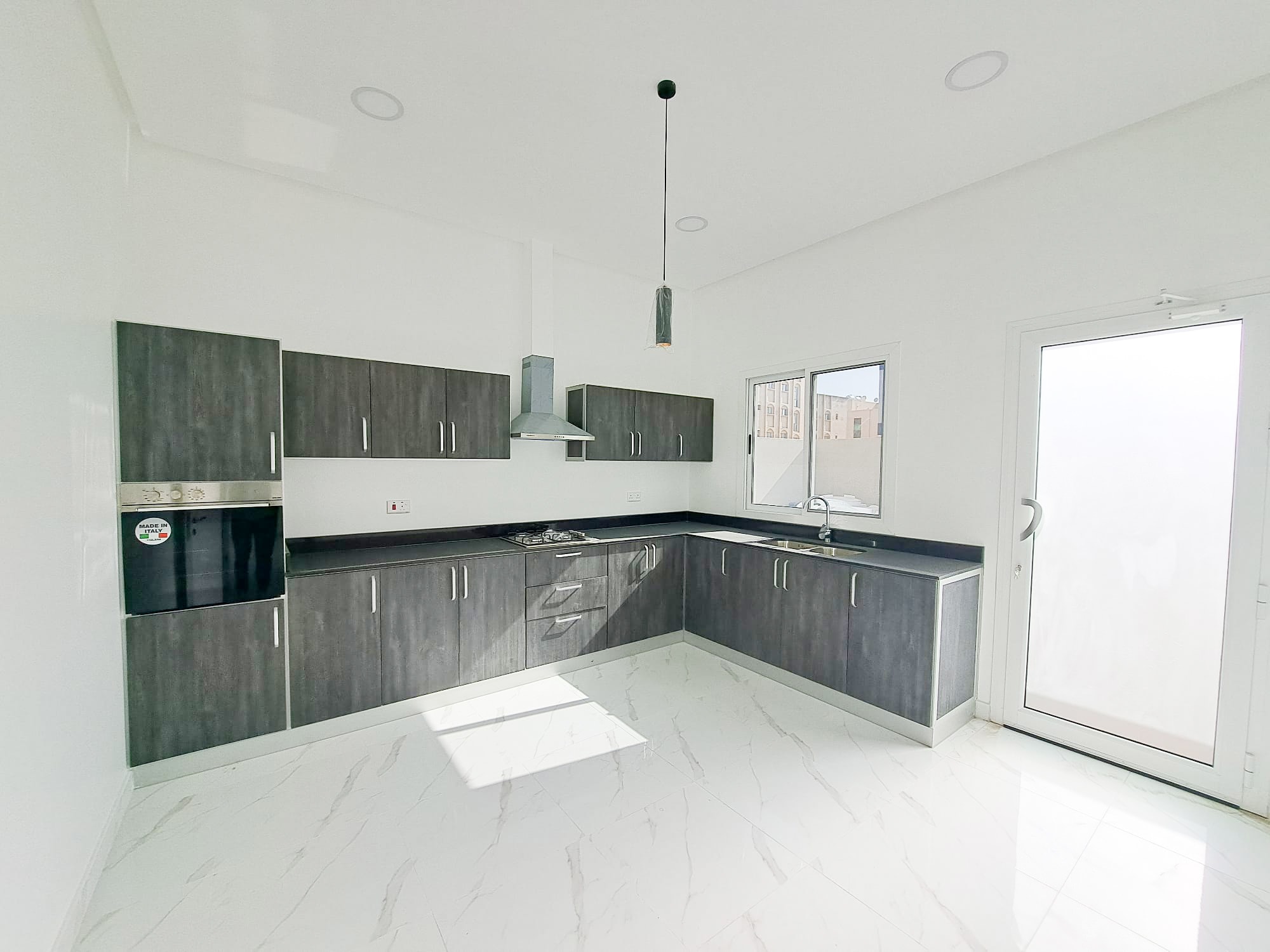 A luxury kitchen with white cabinets and stainless steel appliances in a 4BR Villa located in Al Shakhura.