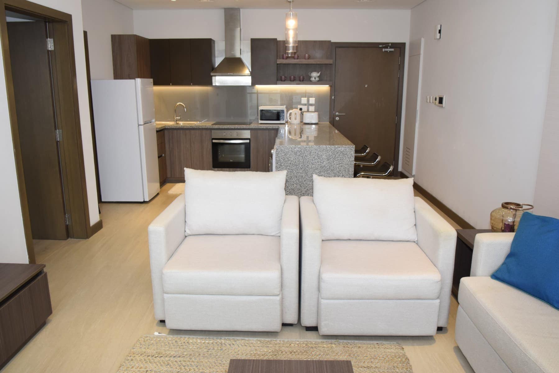 A fully furnished living room and kitchen area in a modern apartment for sale.