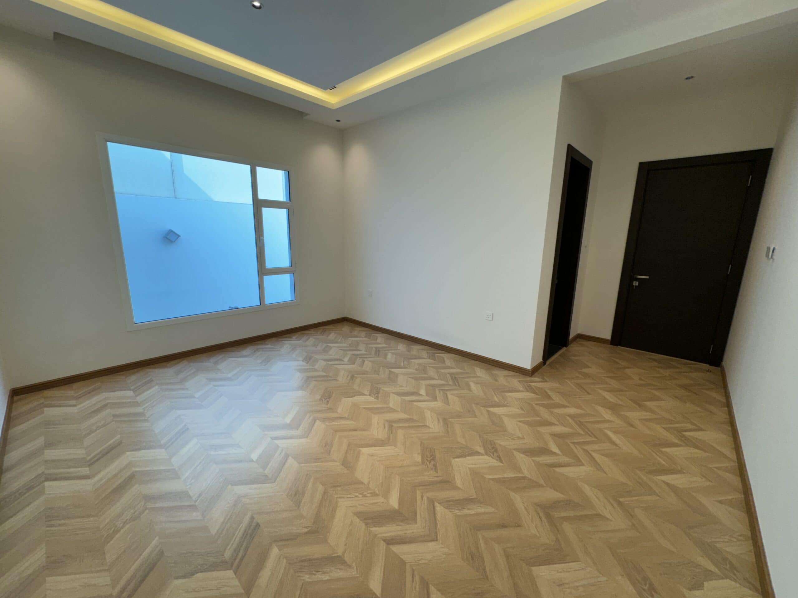 A room with a wood floor and a window overlooking the Villa.