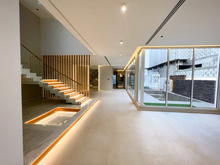 A luxury villa with a glass wall showcasing a modern staircase.