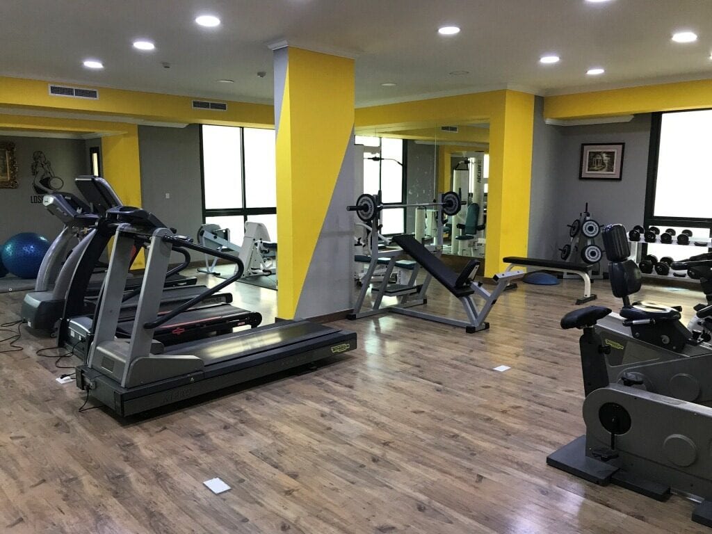 A gym room with yellow walls and yellow tread machines.