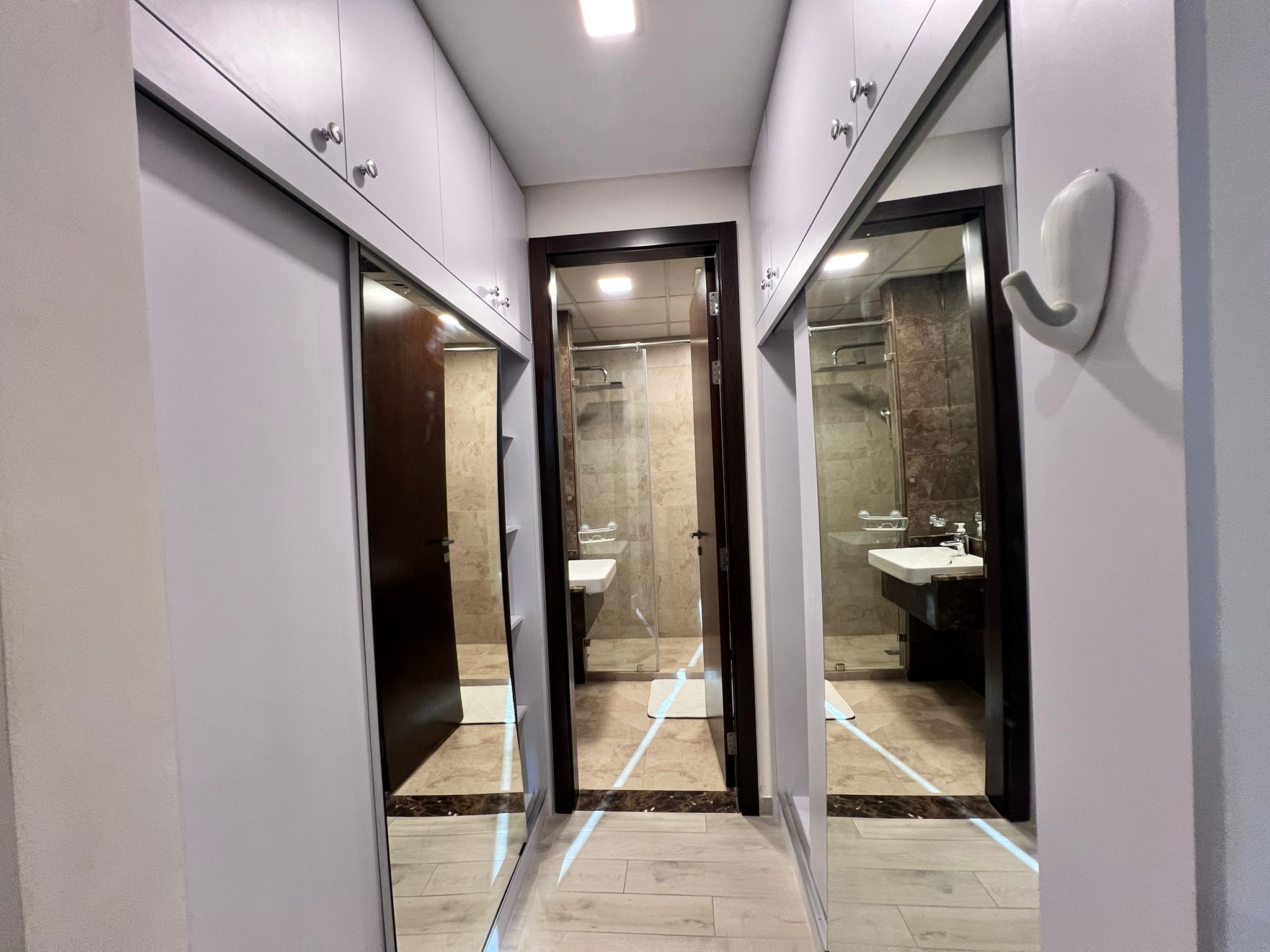 A Juffair hallway adorned with a mirror, presenting a touch of luxury living, and conveniently featuring a sink.