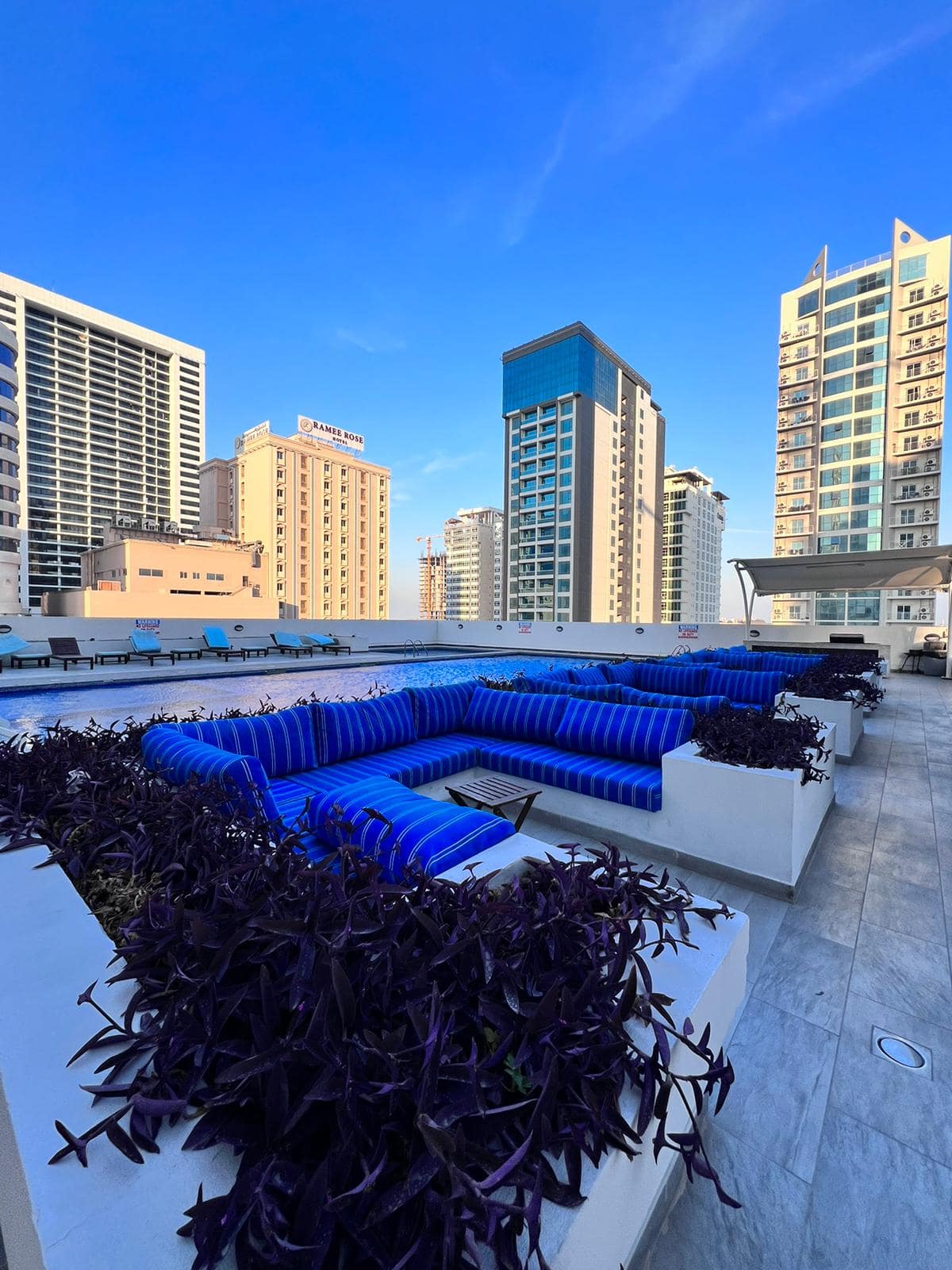 A luxury apartment with a rooftop lounge featuring blue couches and a view of the city.