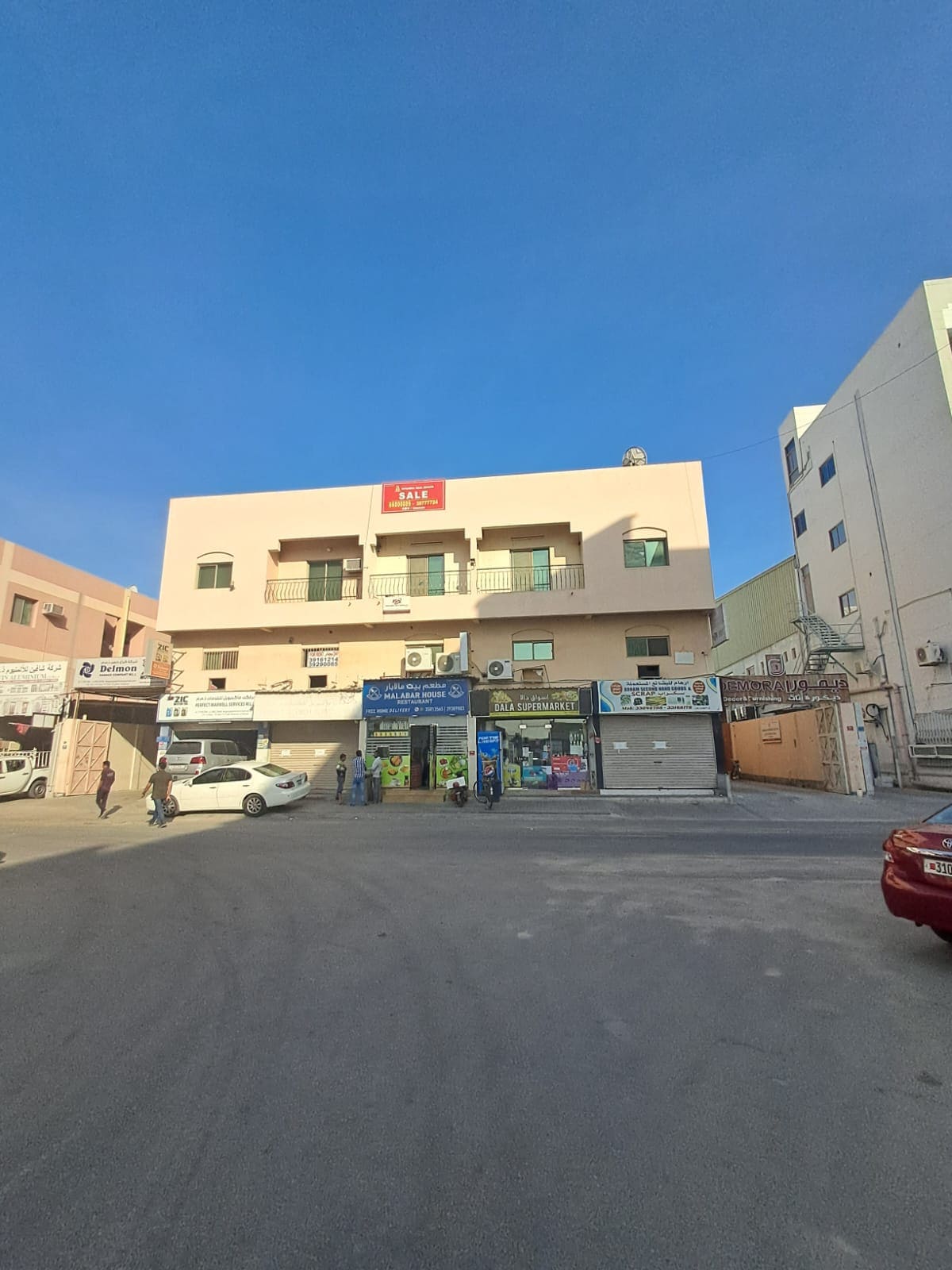 An auto draft building with cars parked in front of it.