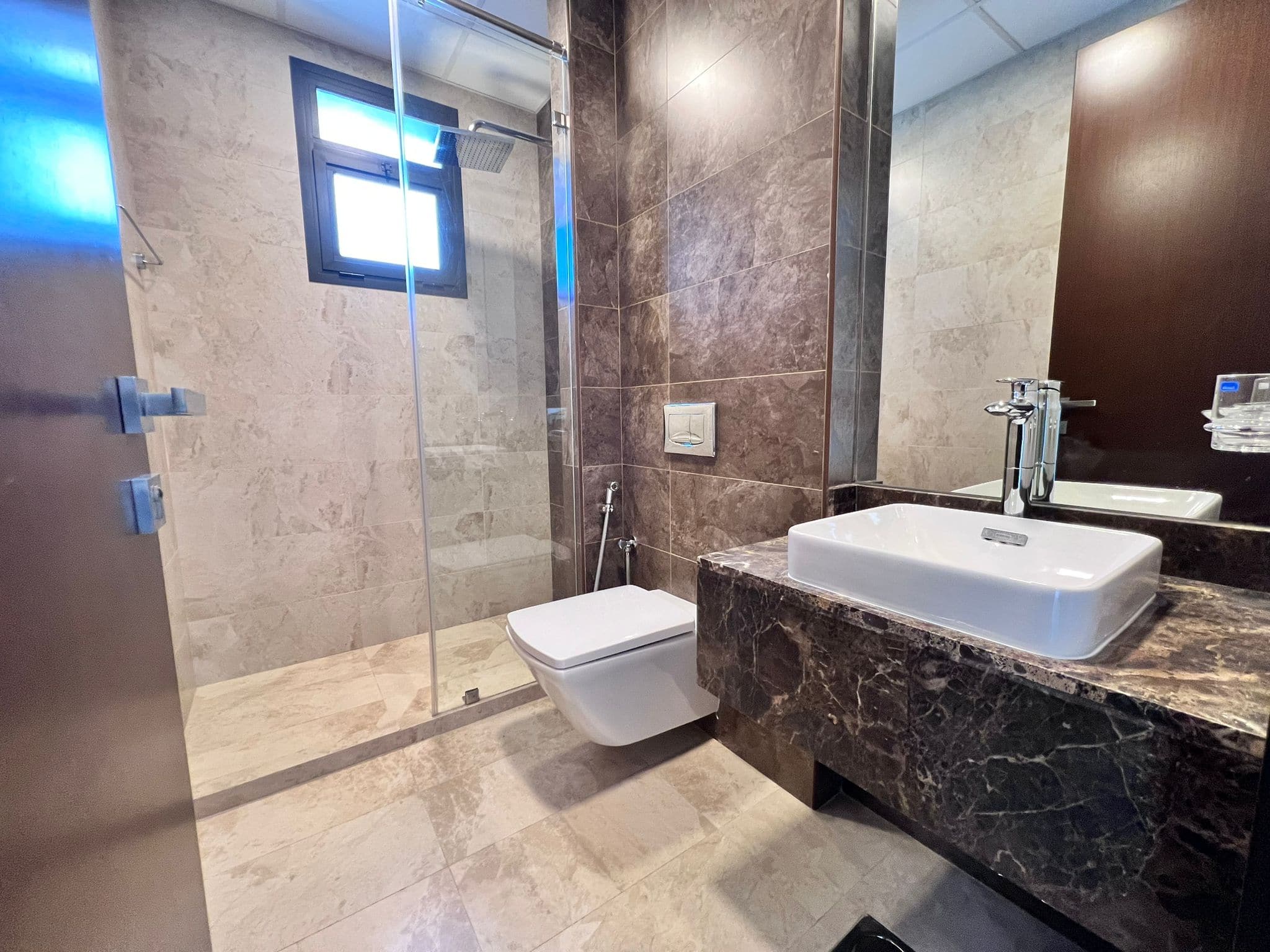 A luxury apartment with a bathroom featuring a toilet, sink, and shower.