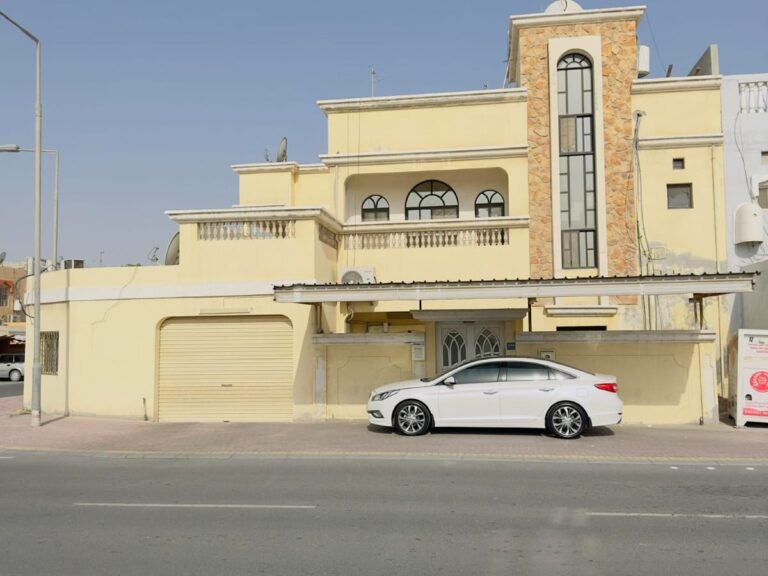 A large villa for sale in Isa Town with a car parked in front of it.