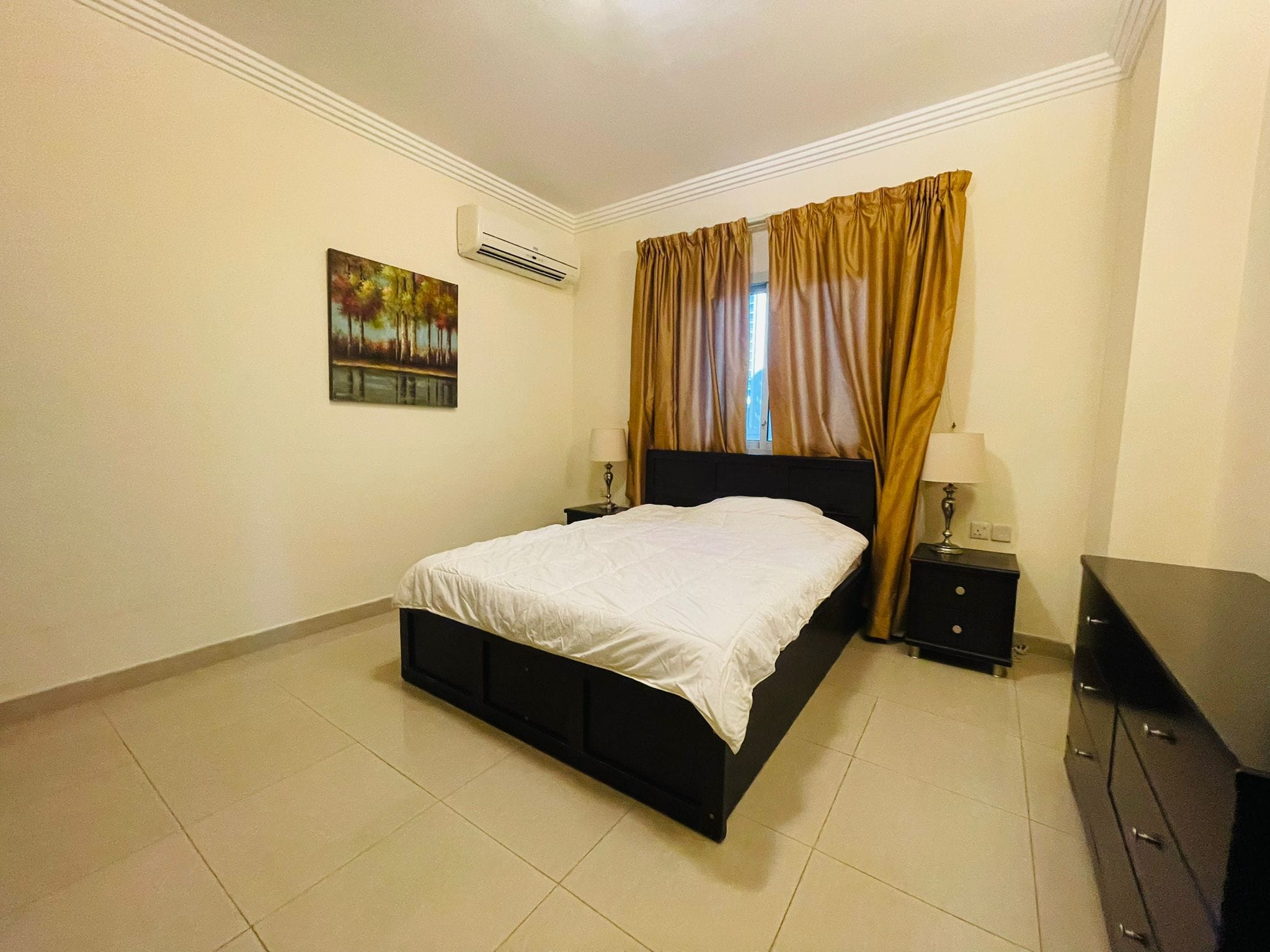 A Juffair bedroom with a bed and a dresser.