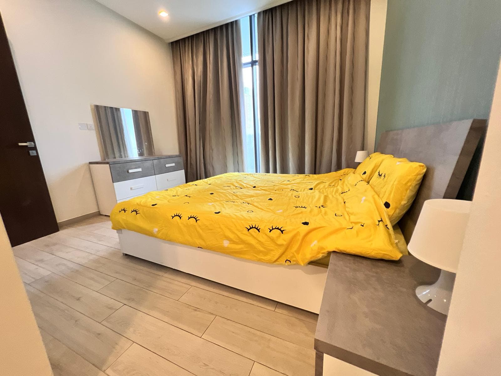 A bed with yellow sheets and a lamp next to a dresser in an auto-themed bedroom.