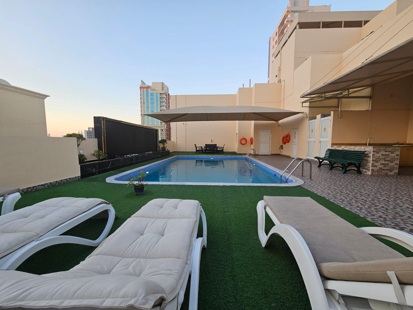 A rooftop swimming pool and lounge chairs on a flat building available for rent in Juffair.