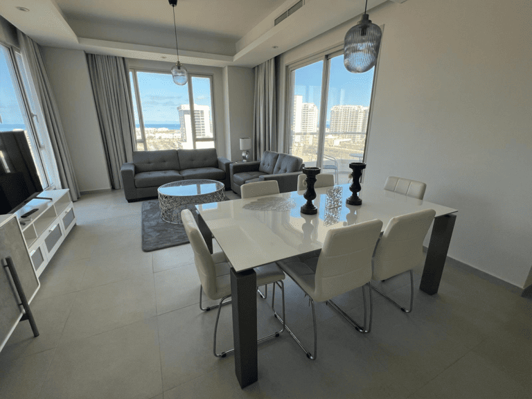 A living room and dining area with a view of the ocean, available for rent in Amwaj in a flat.