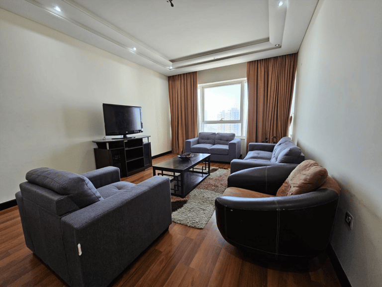 A Sanabis flat for rent with cozy couches and a TV.