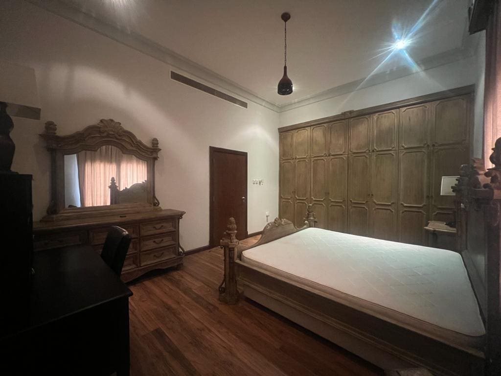 A JUFAAIR bedroom with a bed, dresser and mirror available for rent in a villa.