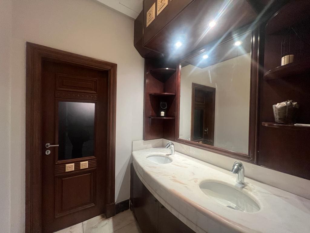 A Jufair villa for rent featuring two sinks and a mirror in the bathroom.