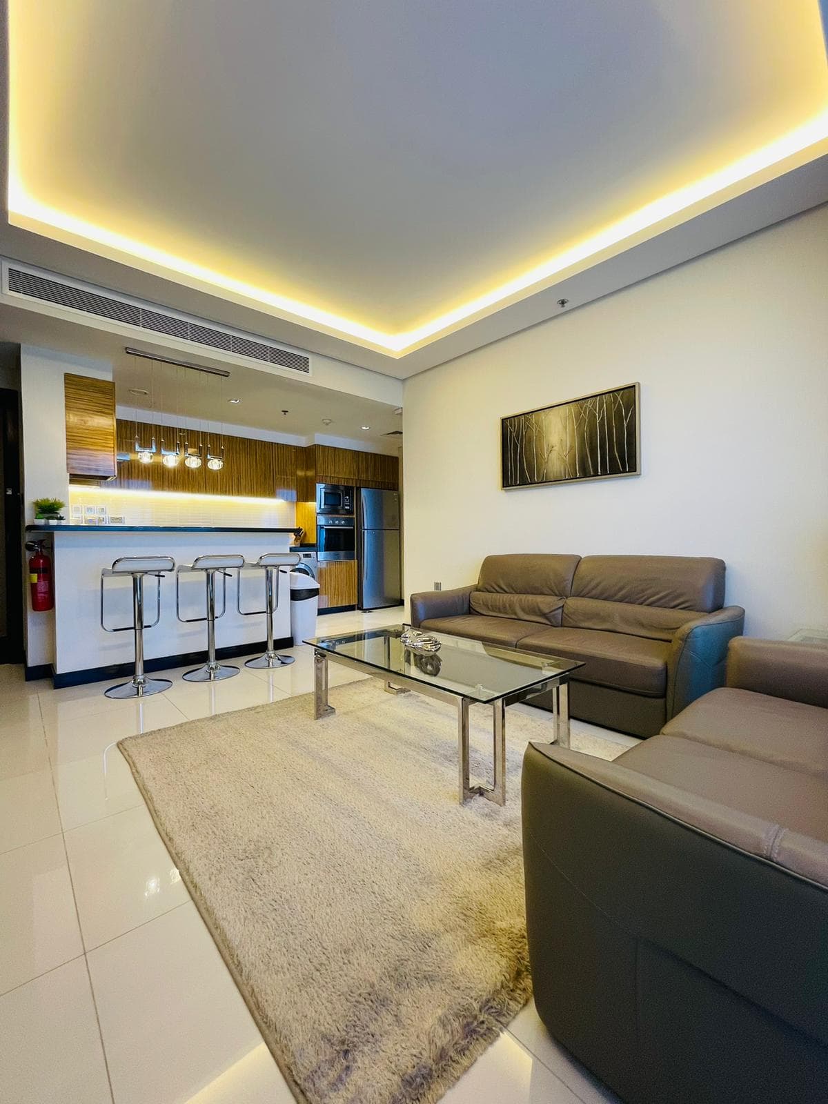 A modern living room and kitchen area in a luxurious 1BR apartment located in Seef.