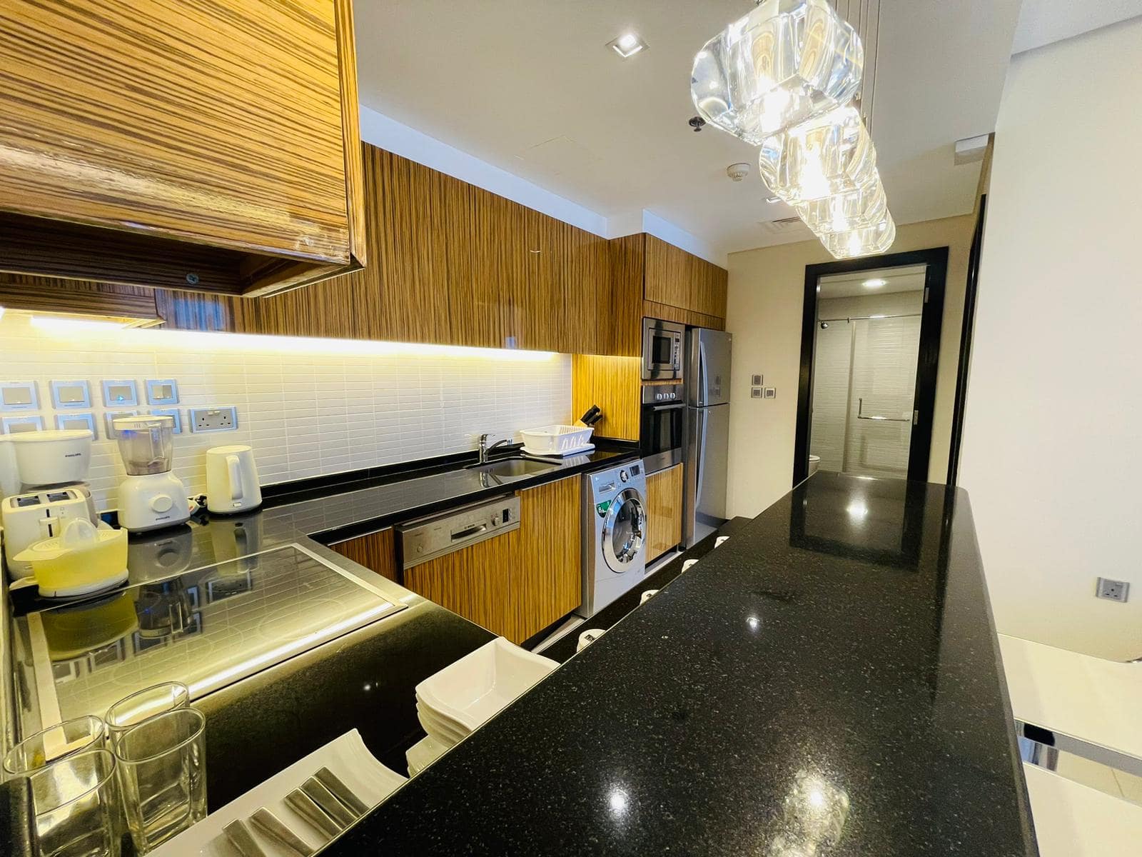 A luxury 1BR apartment in Seef with a kitchenette featuring black counter tops and stainless steel appliances.