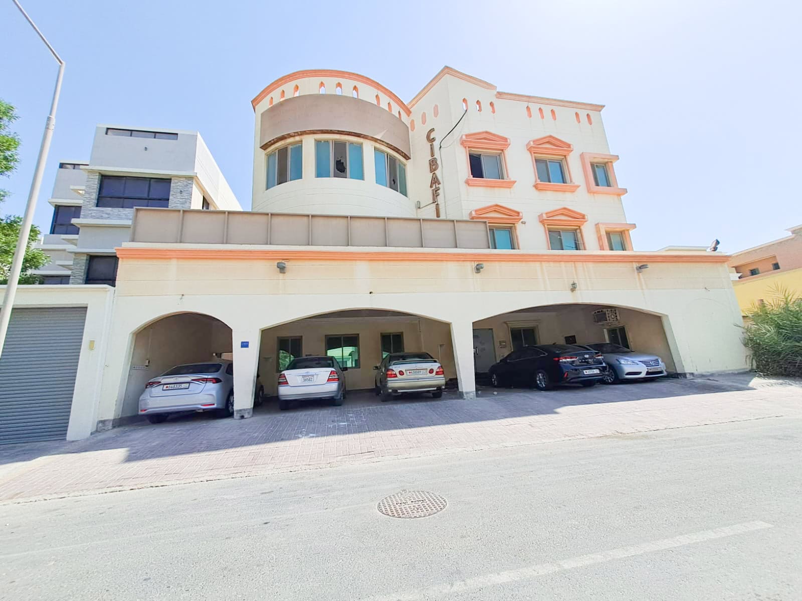 A building for sale with cars parked in front of it in Busaiteen.
