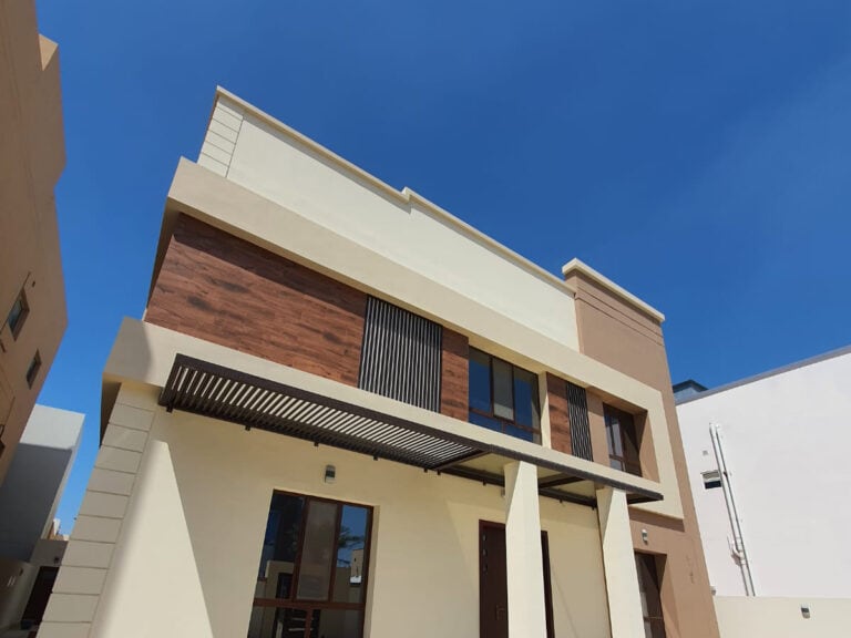 Modern two-story building with a mix of beige stucco and wood facade under a clear blue sky, Auto Draft.