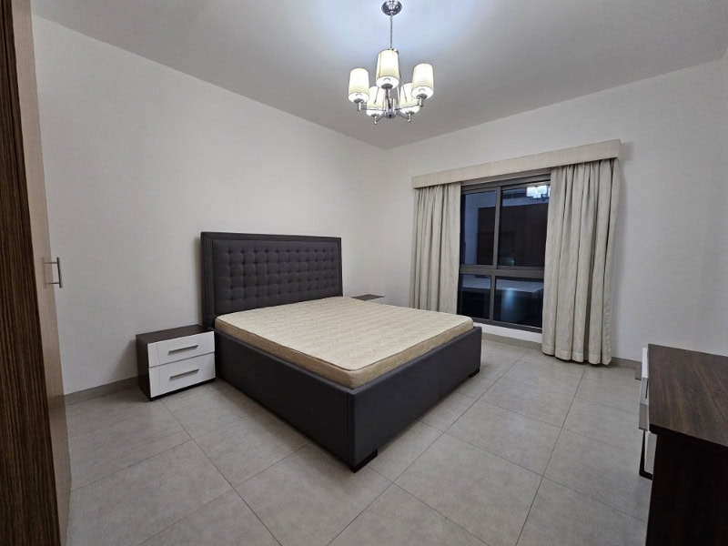 A bedroom with a bed and a dresser for rent in Juffair.