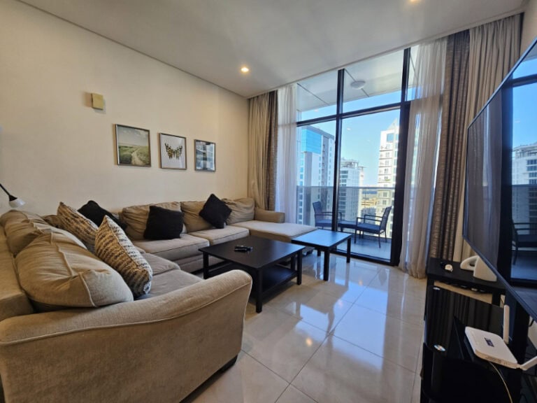 A flat in Juffair with a living room featuring a flat screen TV and a view of the city.