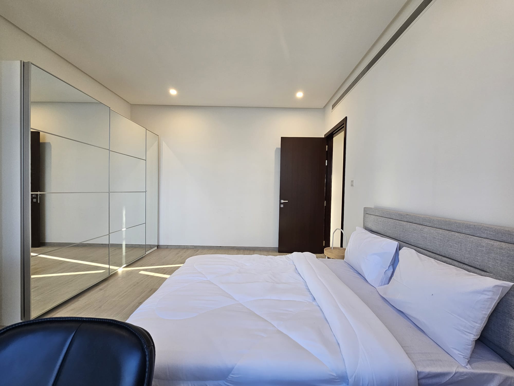 A bedroom with a white bed and mirror.