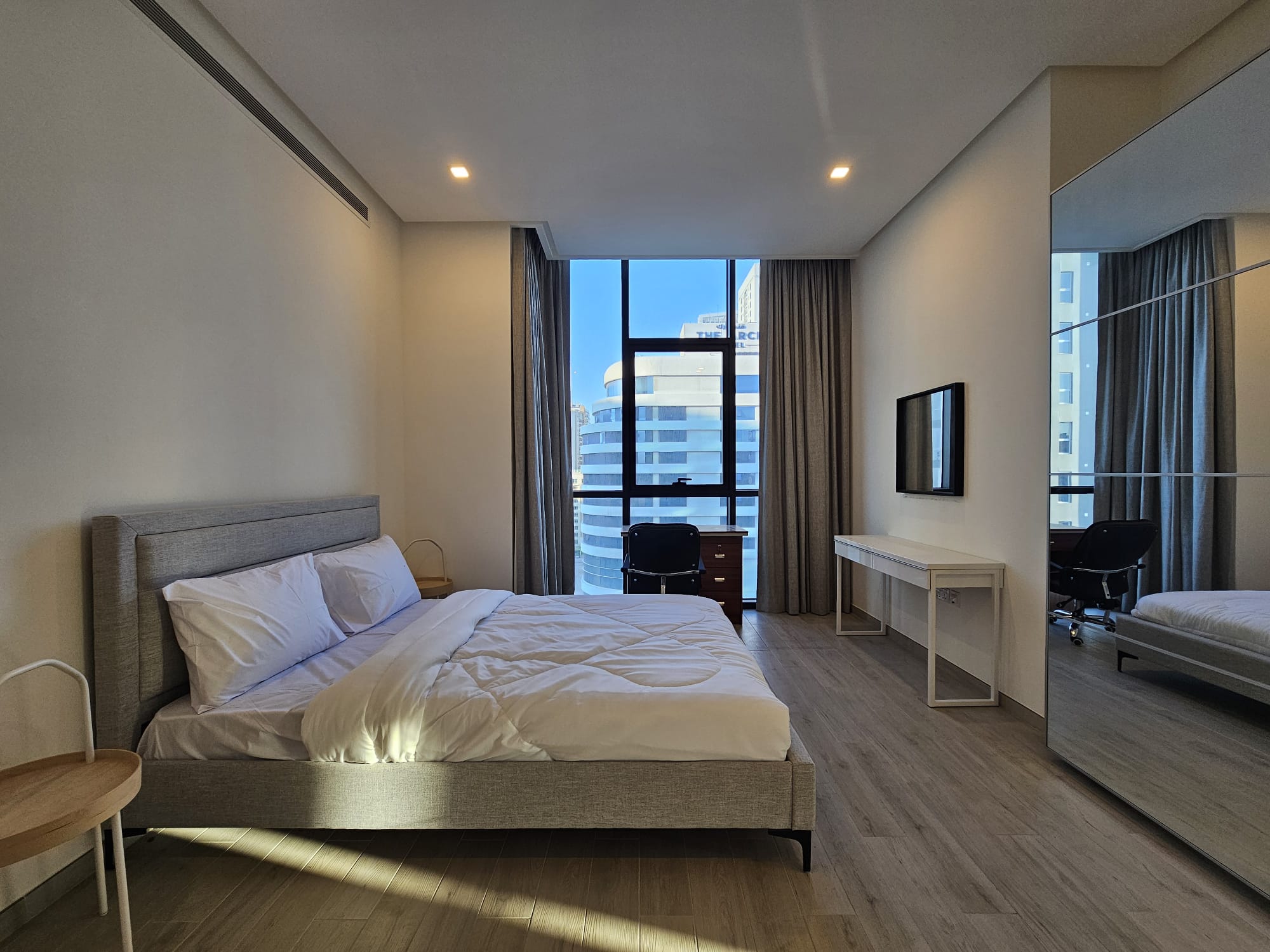 This bedroom offers a view of the city from a large bed.