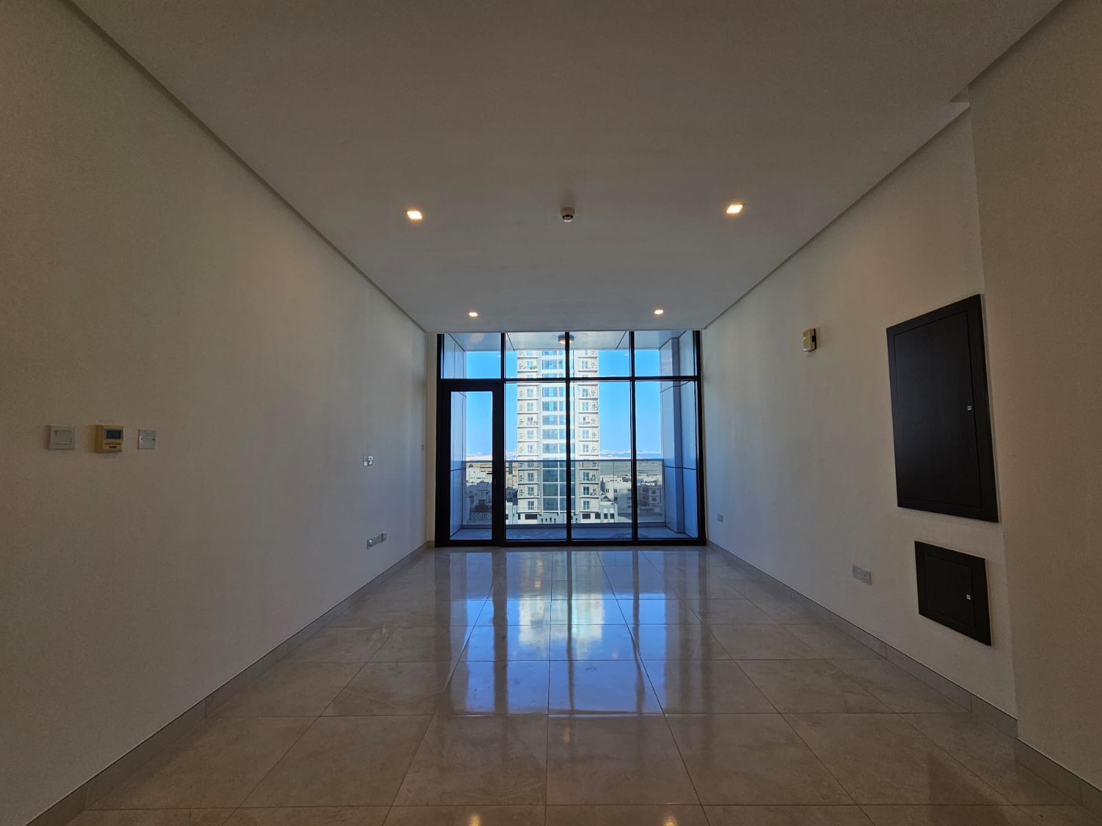 Empty luxury apartment for rent in the Juffair area, with glossy tiles, white walls, and large windows.