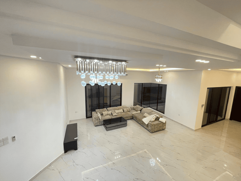 A living room in a Galali flat for rent with a couch and a chandelier.