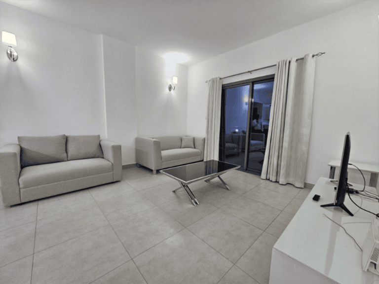 A living room in a Juffair flat for rent, with a glass table and couches.