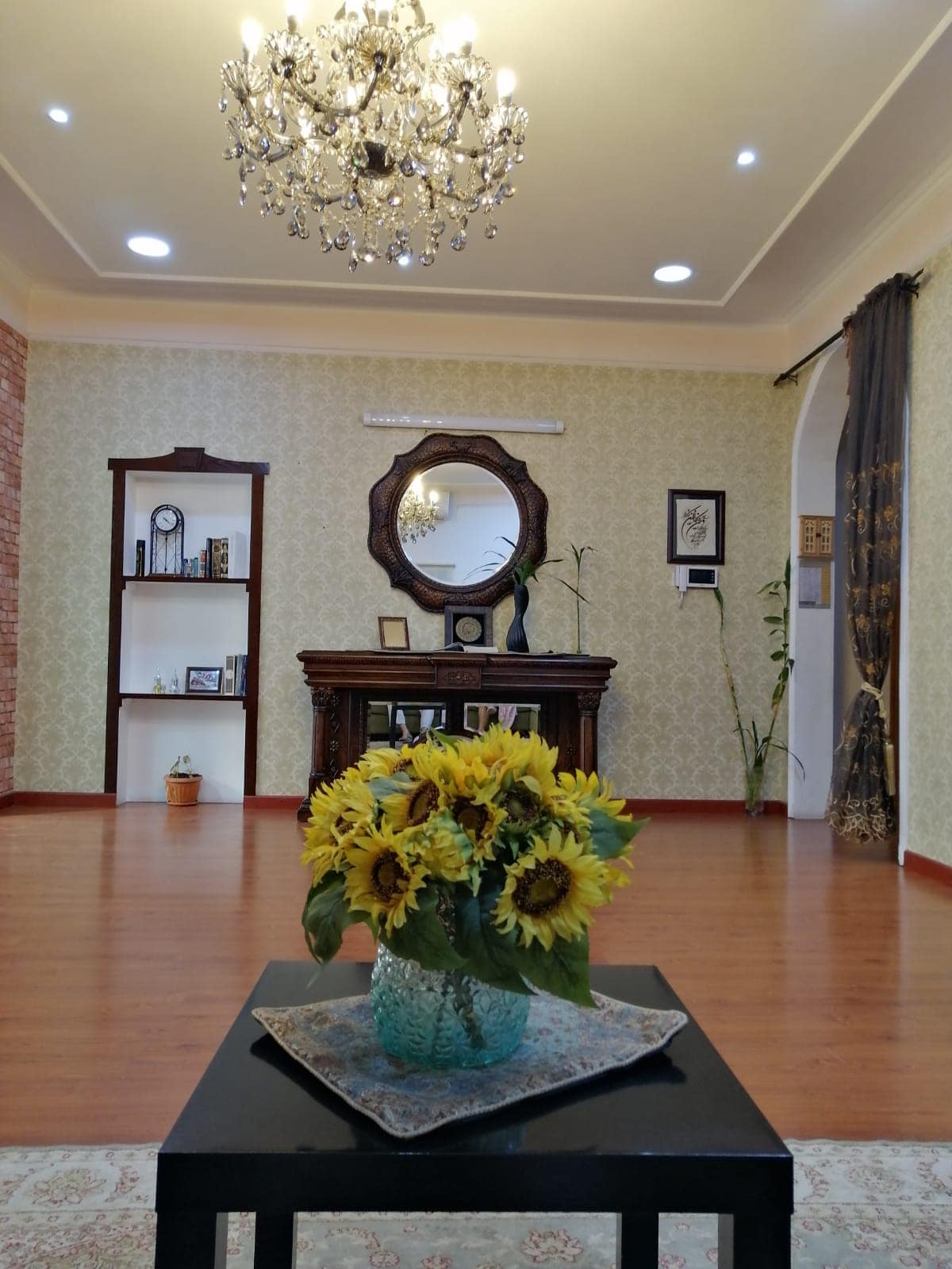 A living room with a vase of sunflowers and a chandelier.