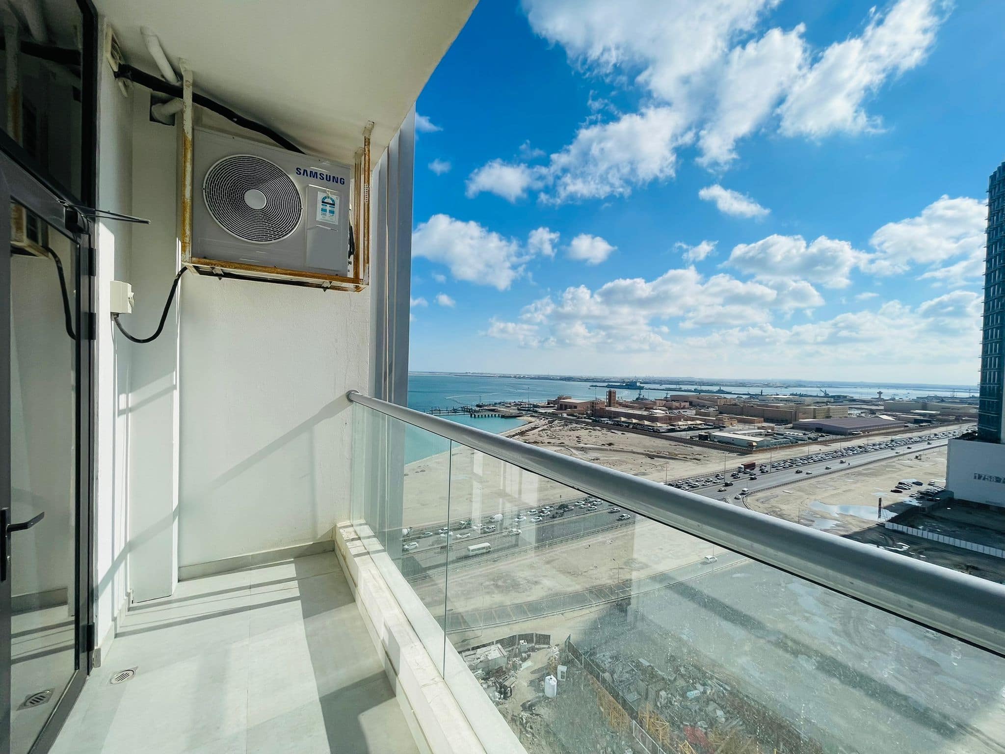 A spacious and modern living balcony with a view of the ocean and city.