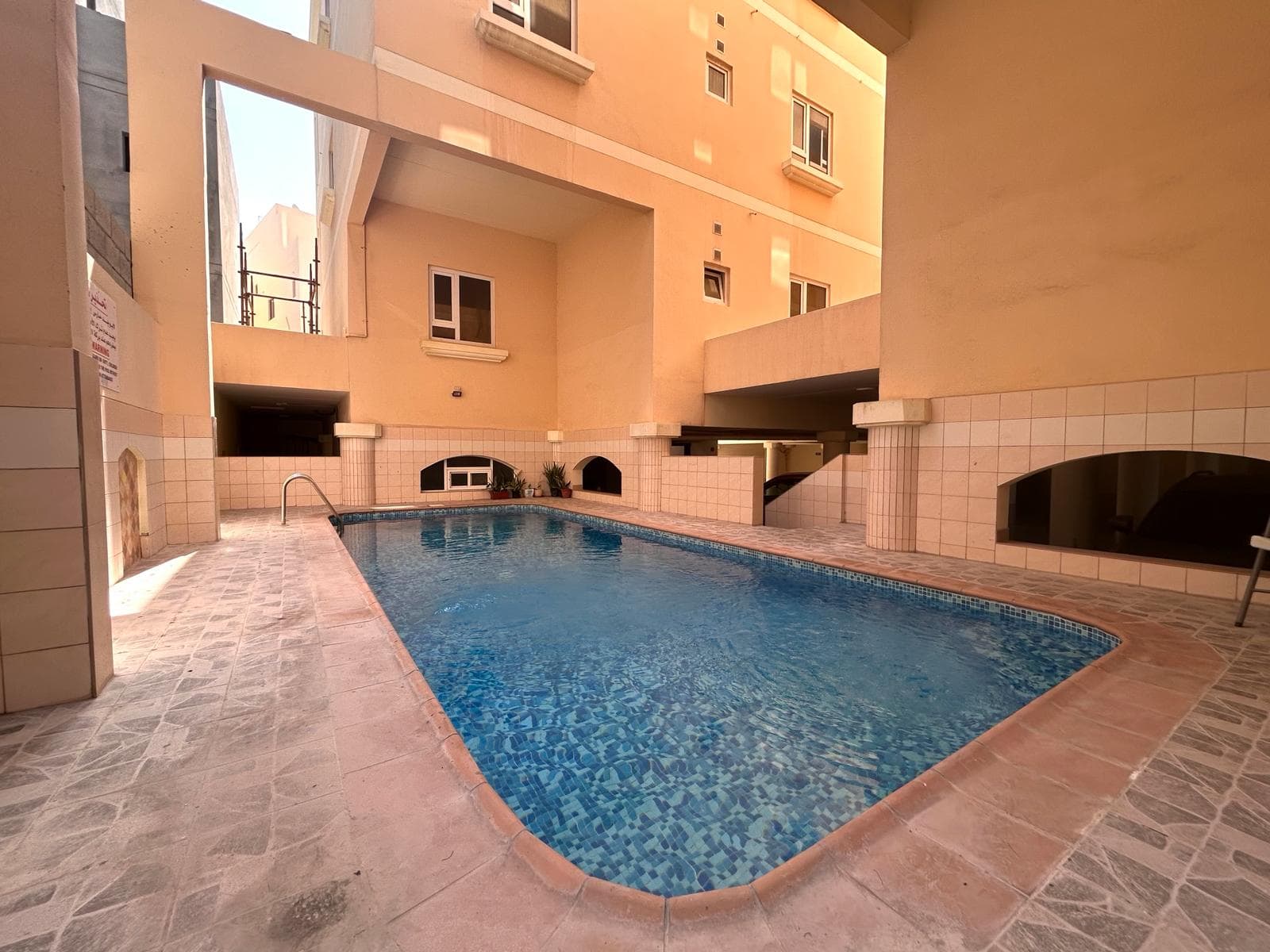 Swimming pool in an urban apartment courtyard surrounded by buildings, available as part of a flat for rent in Saar.