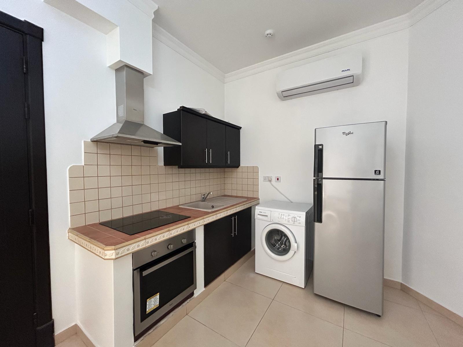 Modern kitchen interior with black cabinets, integrated appliances, and tiled backsplash in a flat for rent in Saar.