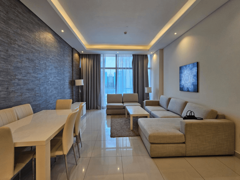 Modern luxury apartment for rent with sectional sofa, dining area, and ambient lighting in Juffair.