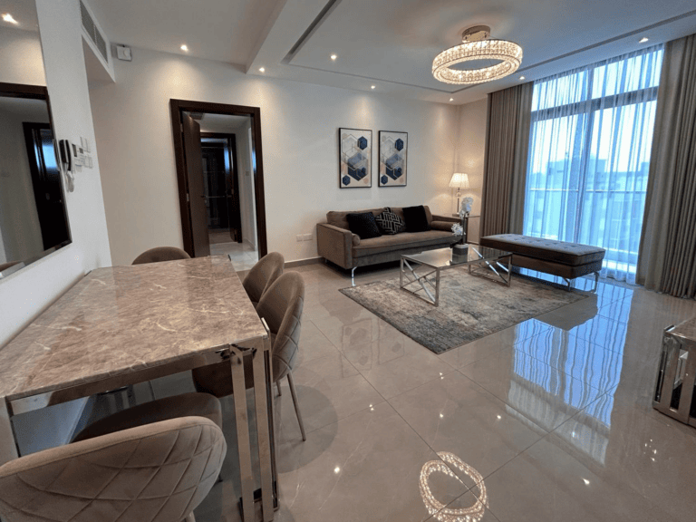 A luxury apartment in Janabiyah featuring a modern living room with marble flooring, a large sofa, and contemporary furnishings.