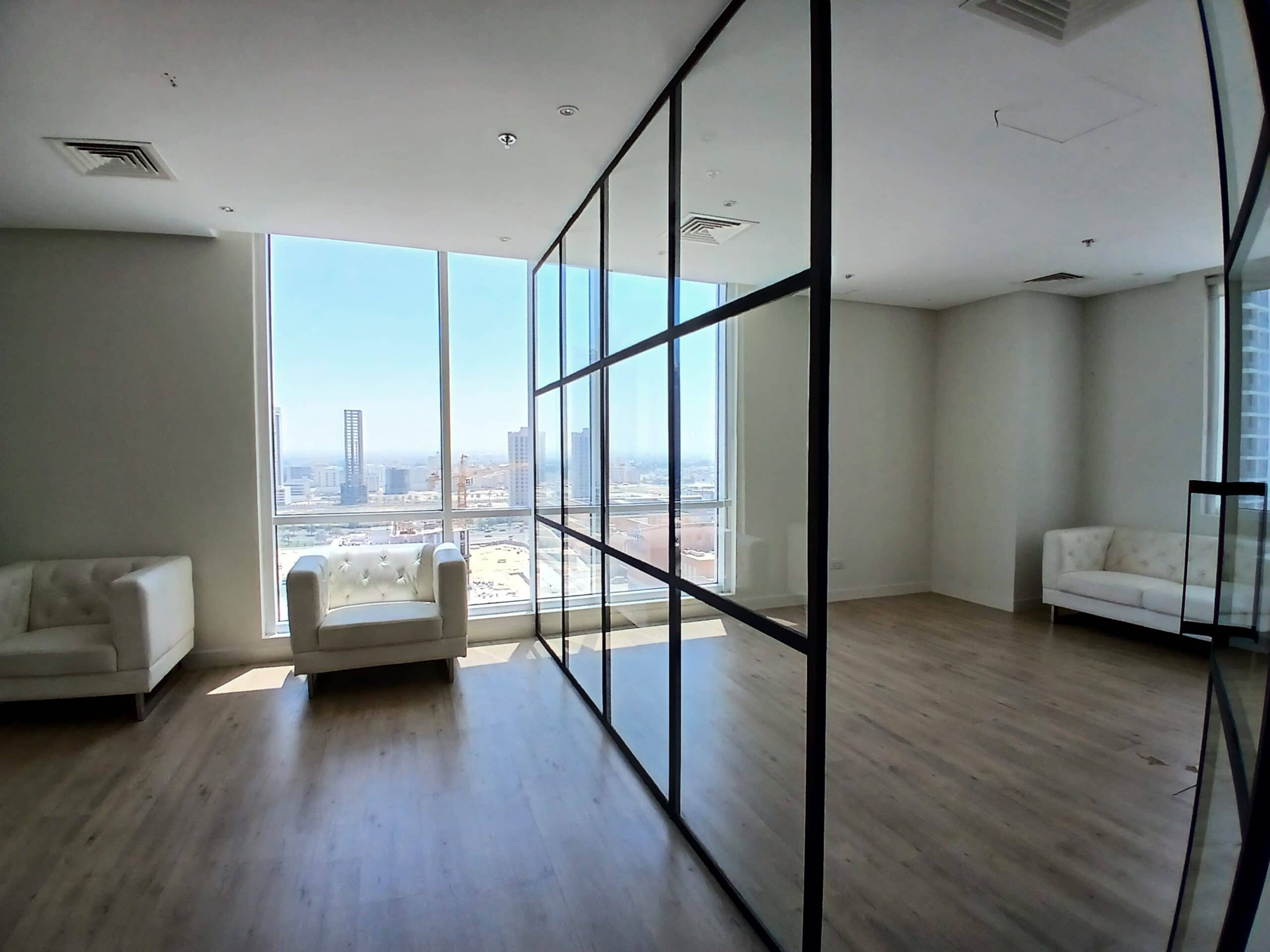 Modern apartment living room with reflective glass partition, two white sofas, and large windows overlooking a cityscape, enhanced for SEO.