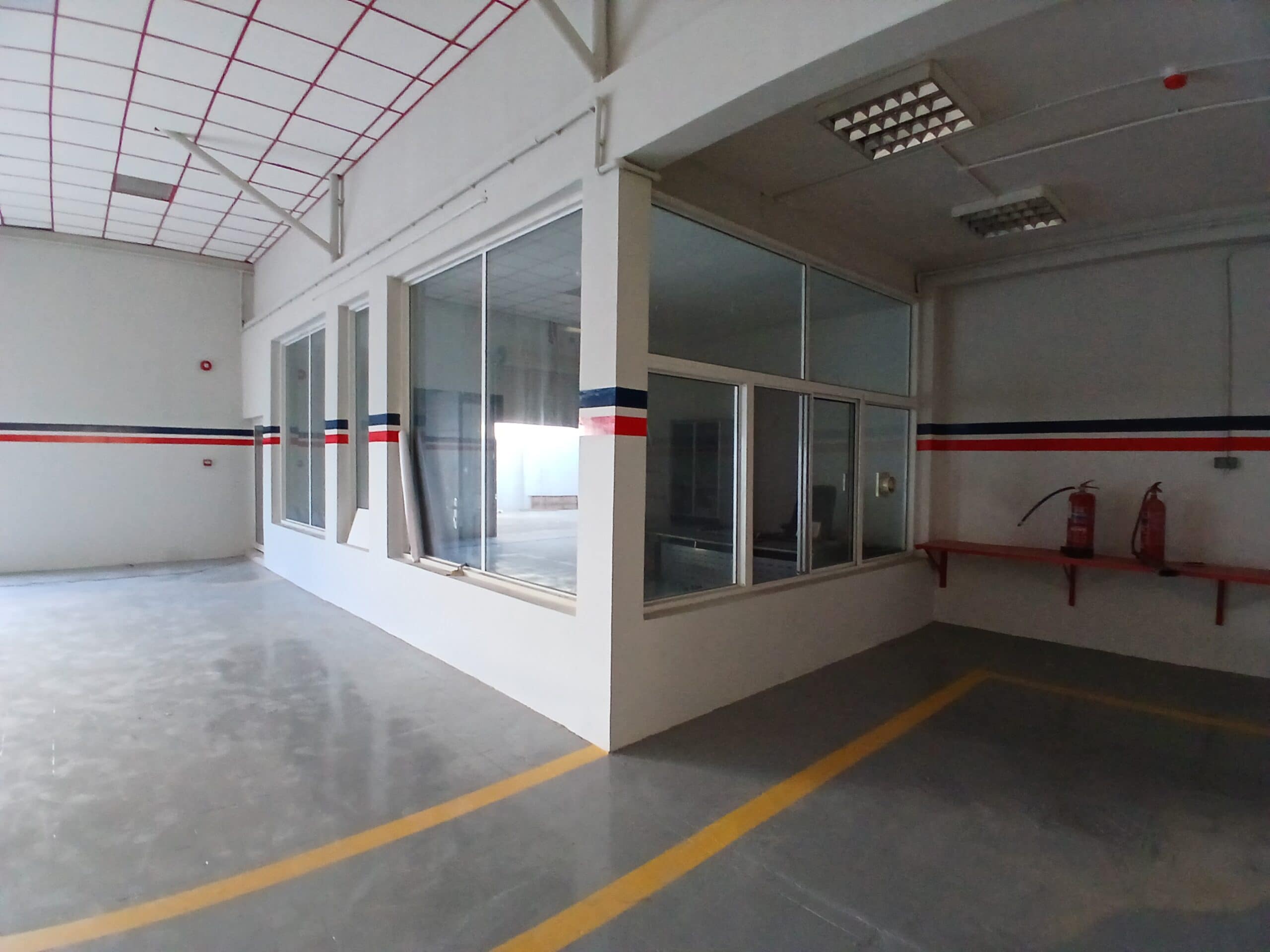 Interior of a spacious, empty room with large windows, reflective floor, and auto draft red and blue stripes on the walls.