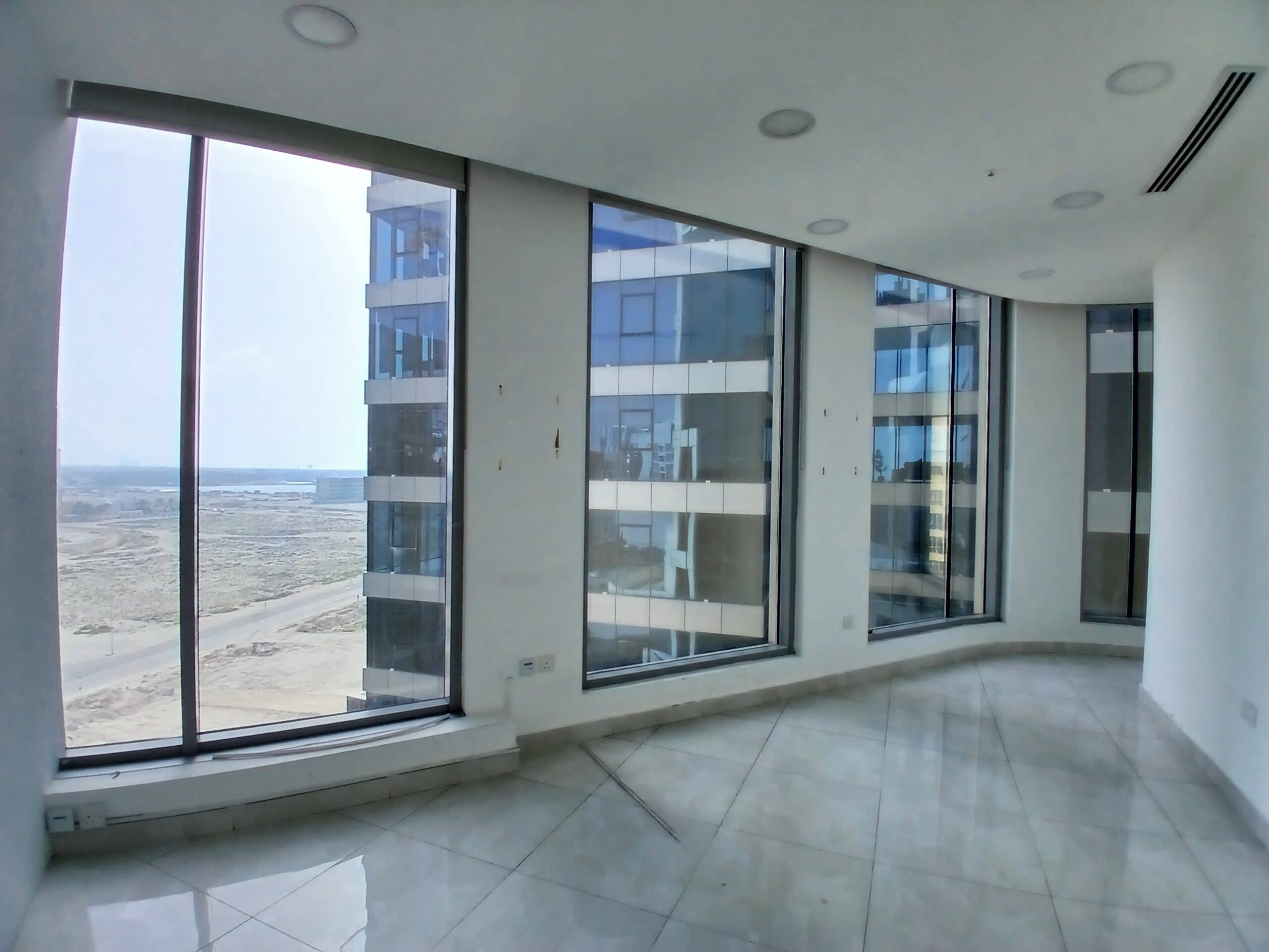 Empty modern apartment room with large floor-to-ceiling windows showing an Auto Draft construction site view.